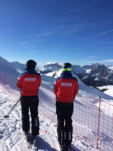 Resdax personal i uniformerna Ryggtavla av Resdax personal på plats i Italien med vy över blå himmer och snötäckta bergstoppar